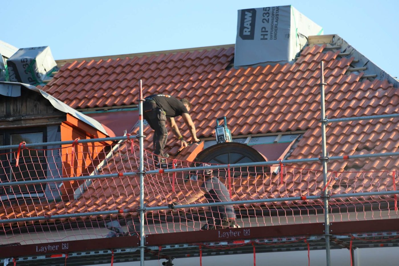 Roofers re-tiling a pitched roof on a UK home